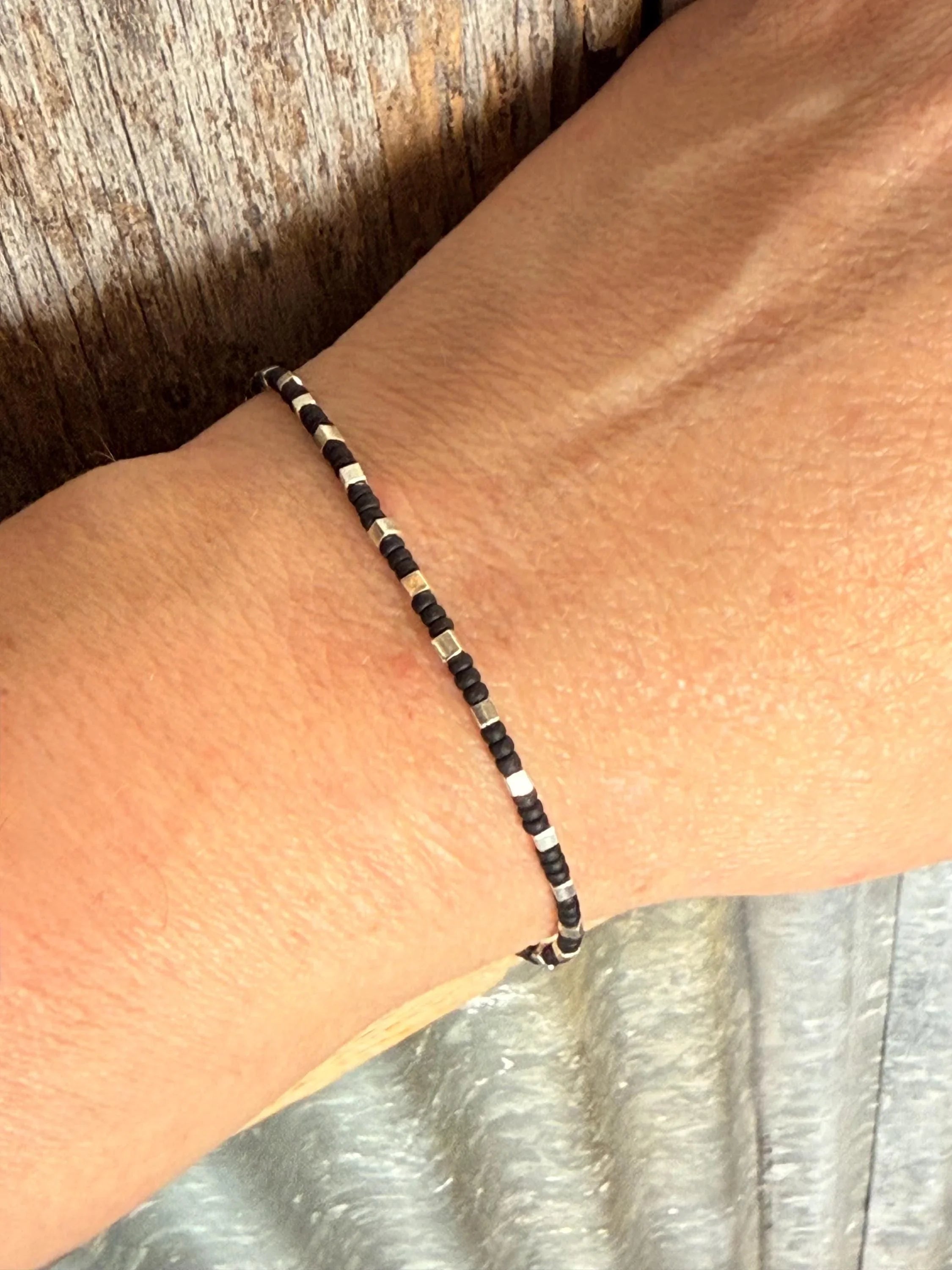 Handmade glass seed bead bracelet in black and silver on wrist, Seed and Soul artistry