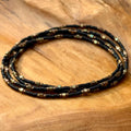 Four handmade black and bronze glass seed bead bracelets on wood, Seed and Soul Artistry jewelry