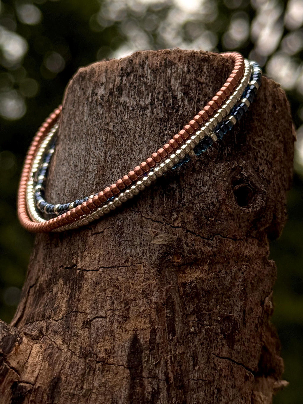 Handmade glass seed bead jewelry necklace draped on tree trunk, Seed and Soul artistry