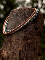 Handmade glass seed bead jewelry necklace draped on tree trunk, Seed and Soul artistry