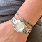 Hand wearing silver watch and green glass seed bead bracelet, handmade jewelry USA