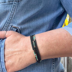 A brown, turquoise, coral and silver beaded wrap bracelet is displayed wrapped around a woman's wrist.