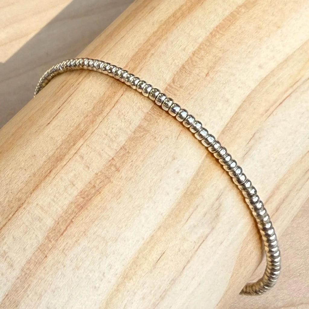 Handmade silver glass seed bead bracelet displayed on light wood by Seed and Soul artistry