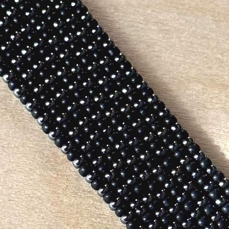 Handmade black glass seed bead bracelet on light wood surface