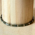 Handmade green and silver glass seed bead bracelet by Seed and Soul artistry on wood display