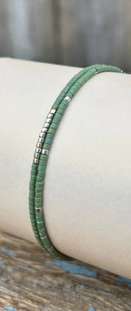 Handmade green glass seed bead bracelet with silver accents on display, Seed and Soul artistry