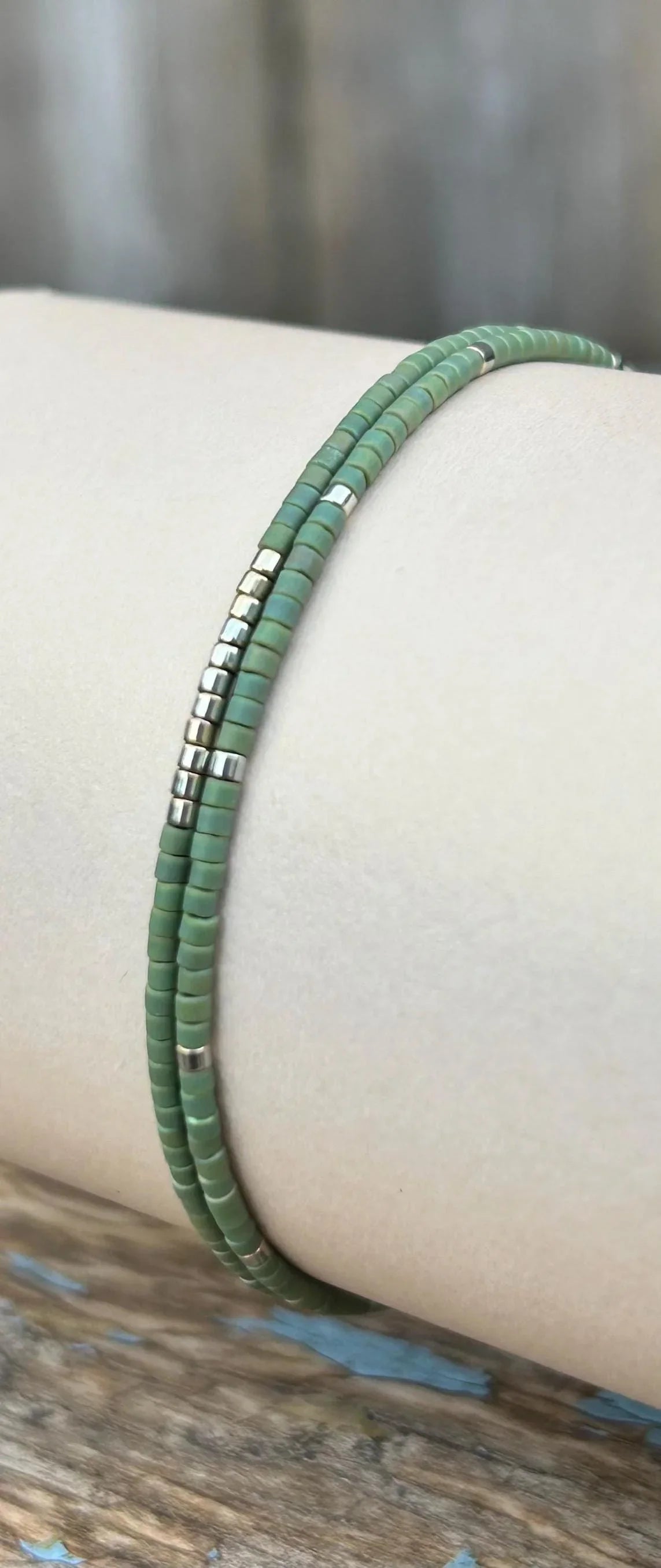 Handmade green glass seed bead bracelet with silver accents on display, Seed and Soul artistry