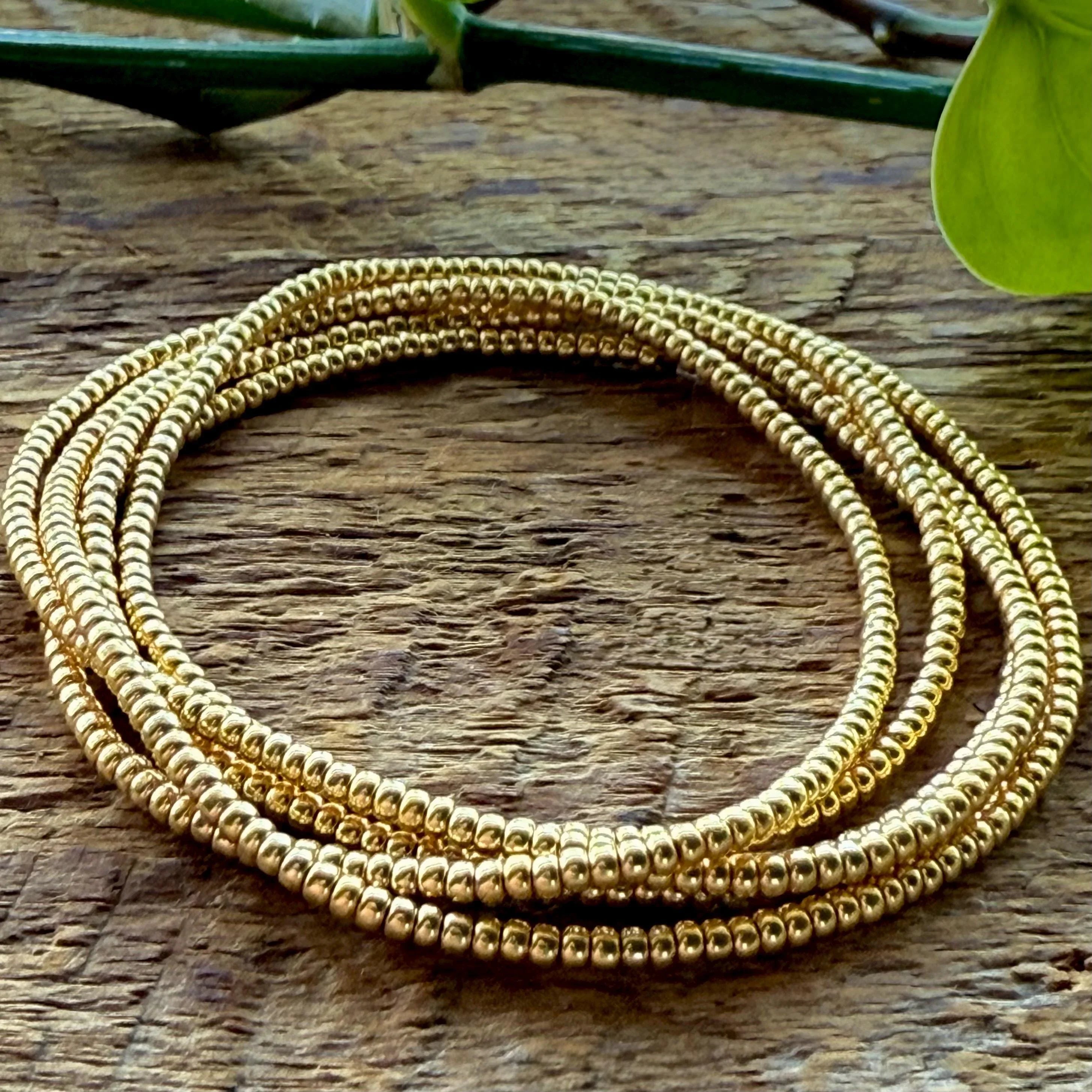gold seed bead necklace coiled up and laid on a wooden background