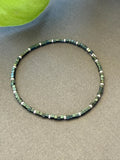 Handmade glass seed bead necklace with green and silver square beads on gray fabric
