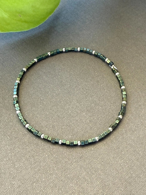 Handmade glass seed bead necklace with green and silver square beads on gray fabric