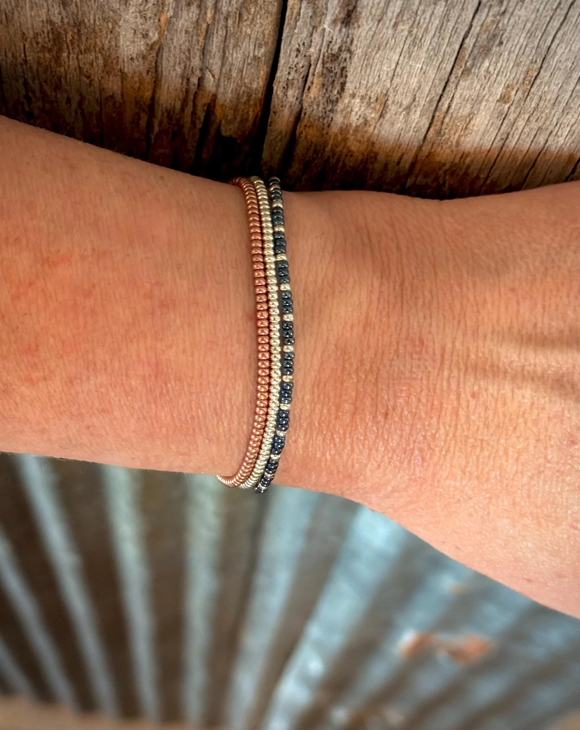 Handmade glass red white and blue seed bead bracelets on wrist, rustic wood background, Seed and Soul artistry