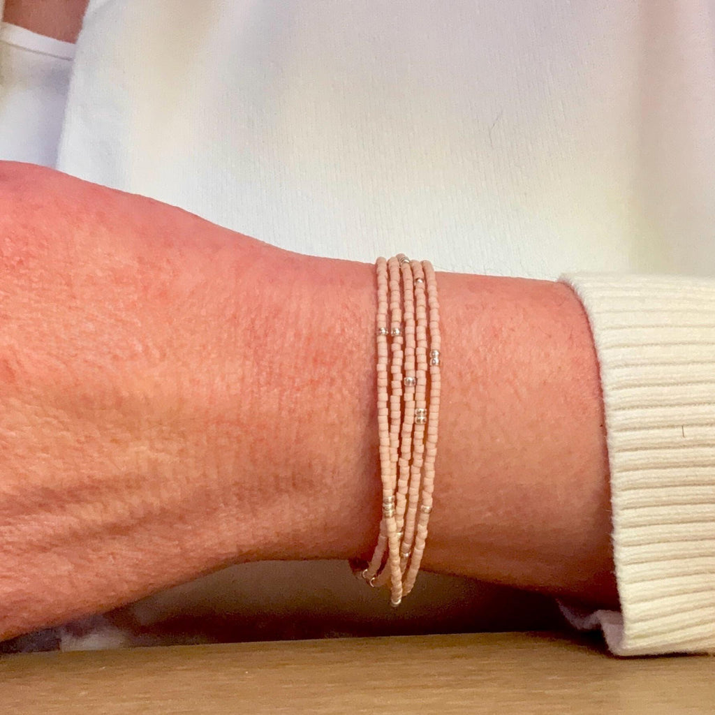 Hand wearing a handmade pink glass seed bead bracelet with silver accents