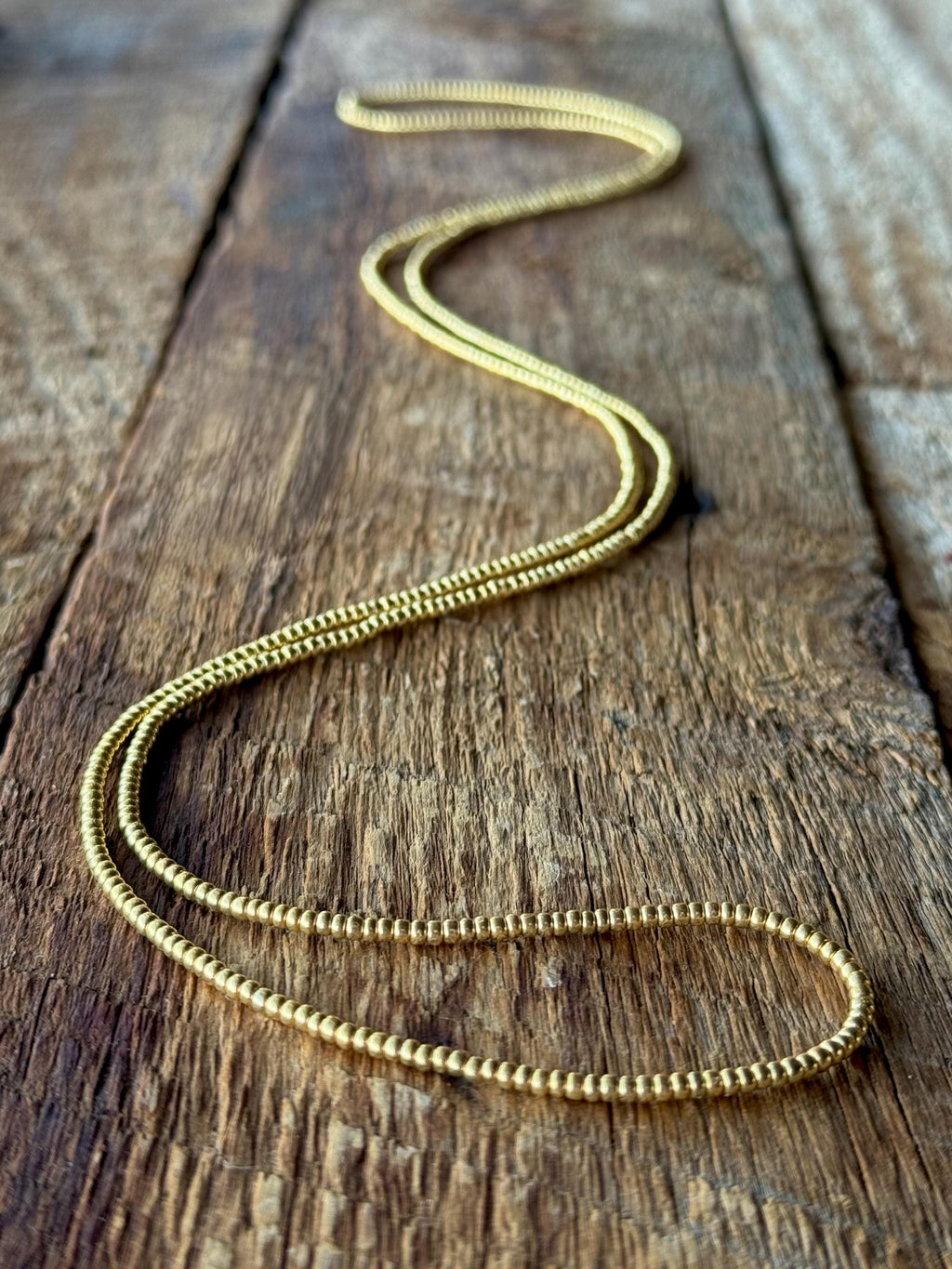 Handmade gold glass seed bead necklace on rustic wood surface, Seed and Soul artistry
