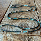 Handmade glass seed bead necklace with brown and turquoise beads laid out on a rustic wooden board.