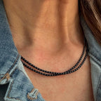 Handmade black glass seed bead necklace layered on a neck, worn with a denim jacket.