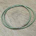 Handmade green glass seed bead bracelet with silver accents on wood surface