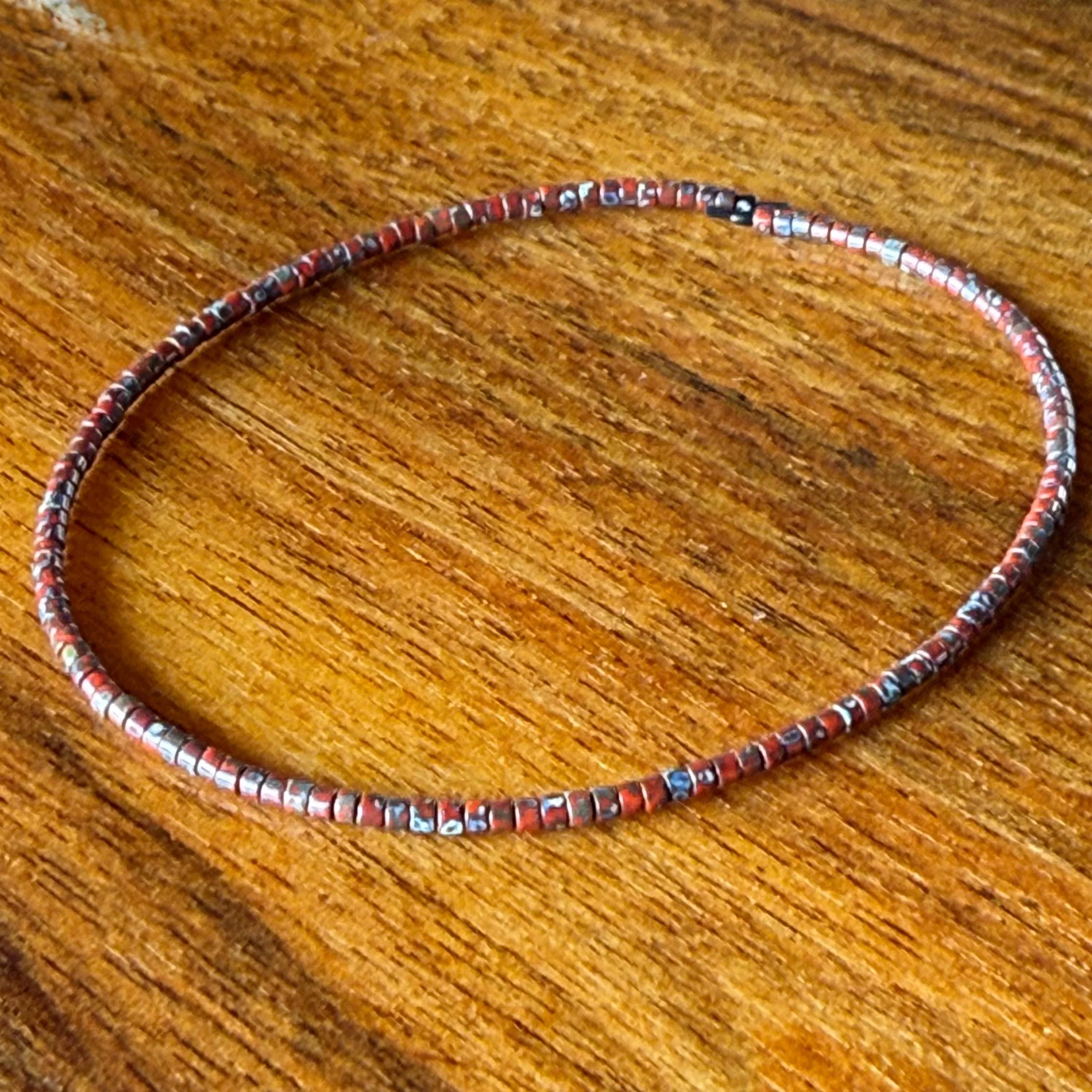 Handmade red glass seed bead bracelet on wood surface, Seed and Soul artistry jewelry