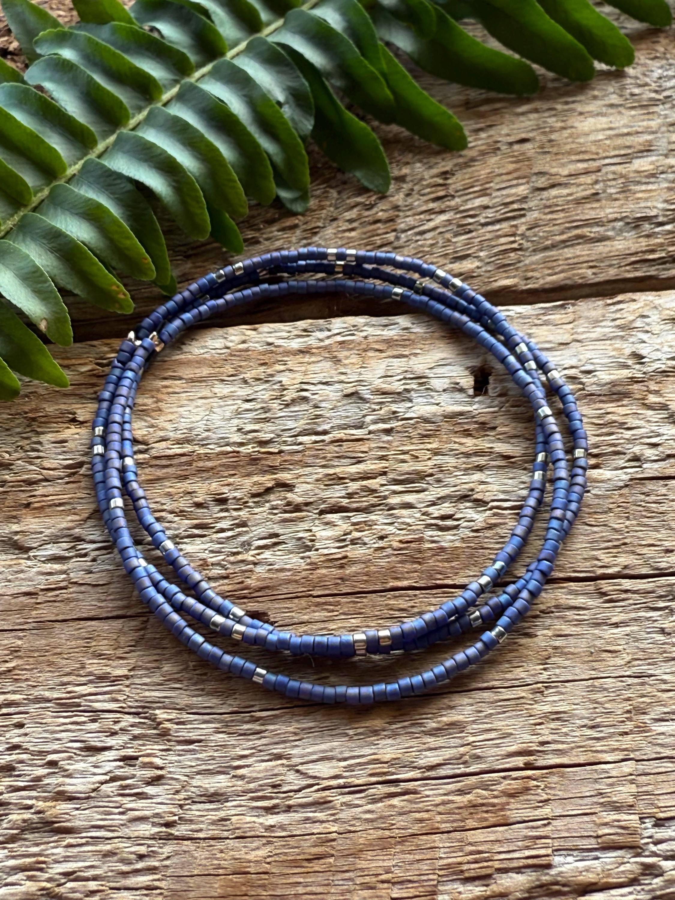 Handmade blue glass seed bead bracelet on rustic wood with green fern, Seed and Soul artistry
