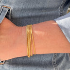 Gold glass seed bead bracelet stack, handmade jewelry shown on wrist in denim sleeve