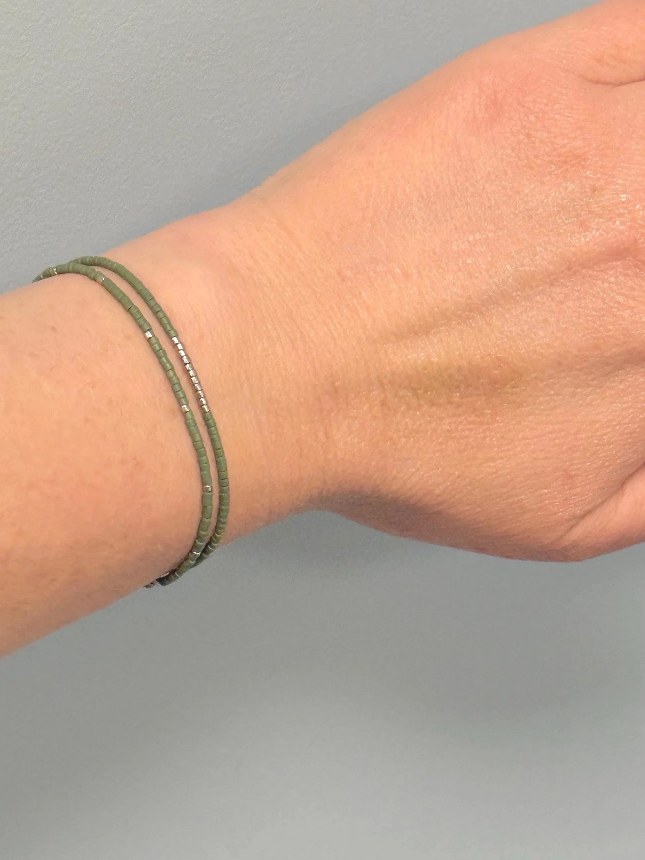 Hand wearing handmade green glass seed bead bracelet by Seed and Soul Artistry
