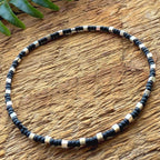 Handmade black and silver glass seed bead necklace on rustic wood surface, Seed and Soul artistry