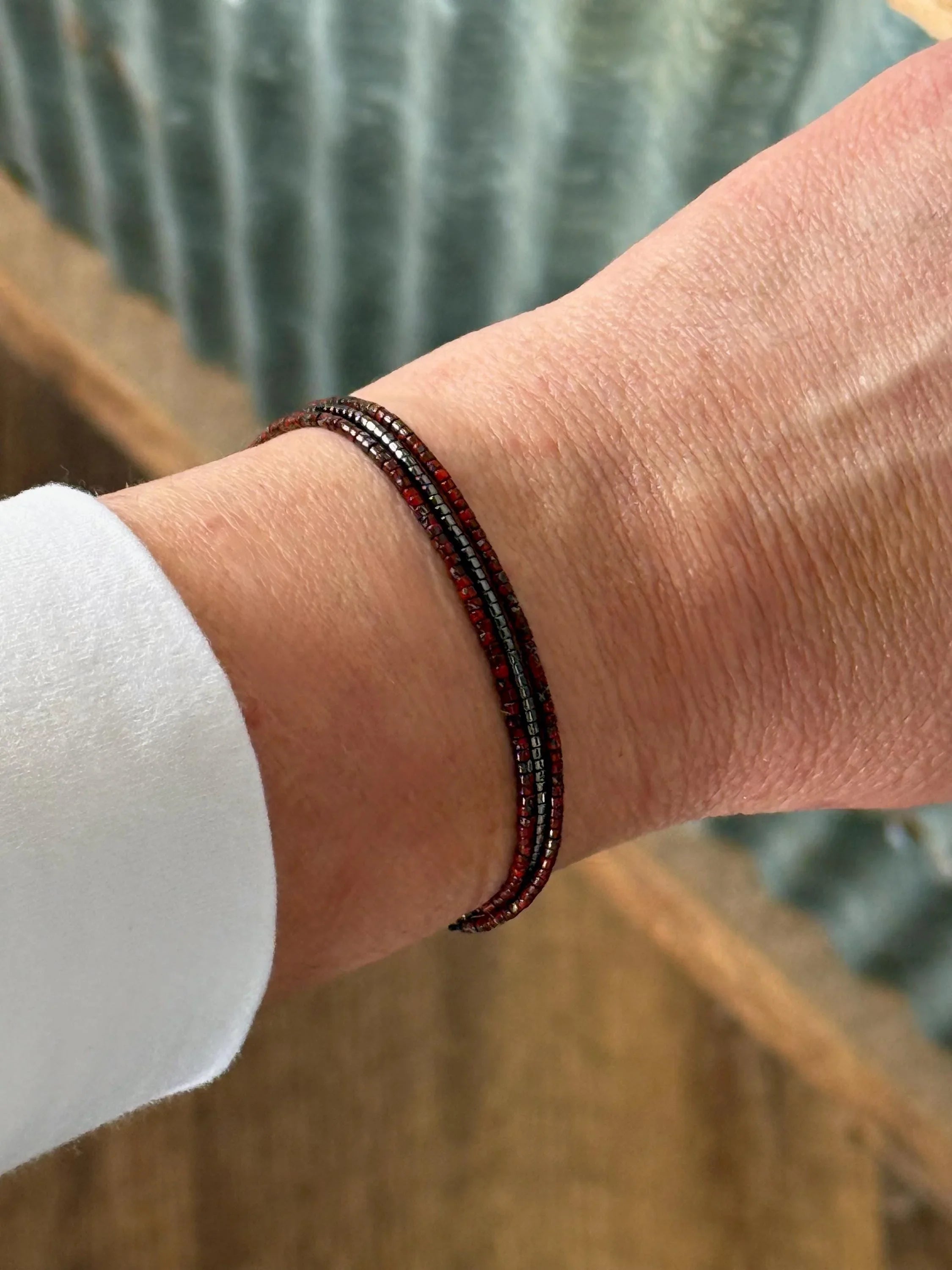 Hand wearing handmade glass seed bead bracelet in red and black from Seed and Soul Artistry
