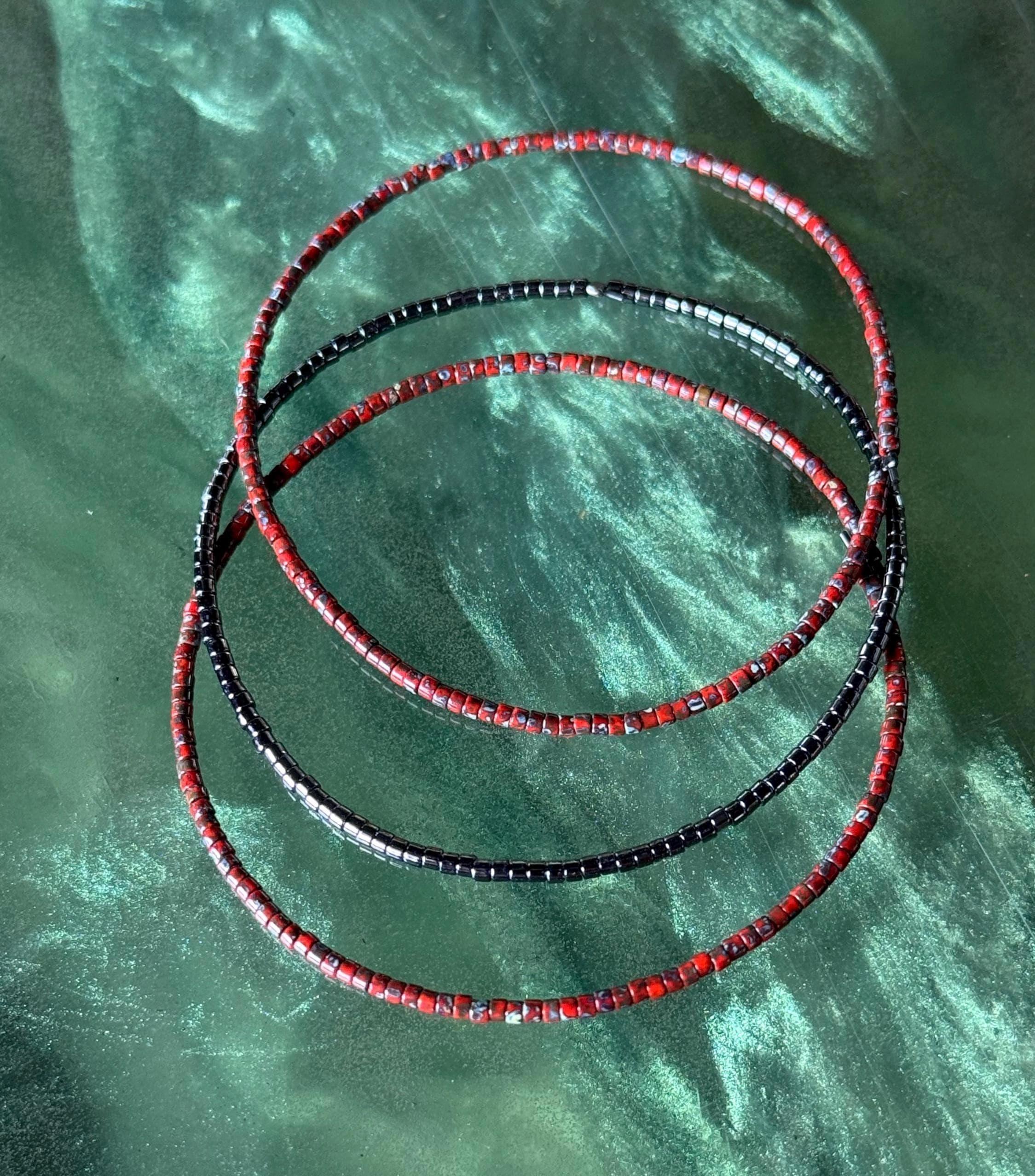 Handmade red and black glass seed bead bangles on green background, Seed and Soul artistry